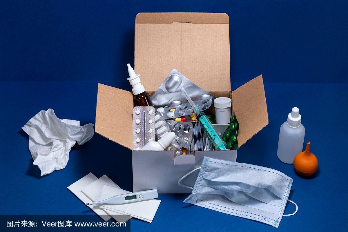深藍(lán)色背景的紙板箱,里面有醫(yī)療用品.泡罩包裝的藥片.感冒和流感季節(jié)